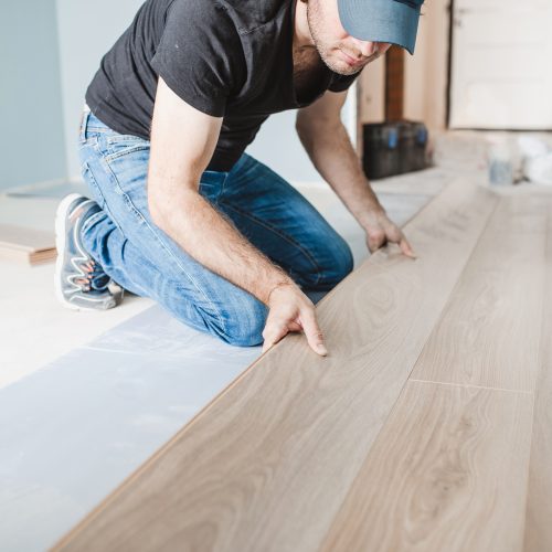 A technician carefully installs LVP flooring in a new home, offering a durable, affordable, and beautiful floor that lasts.